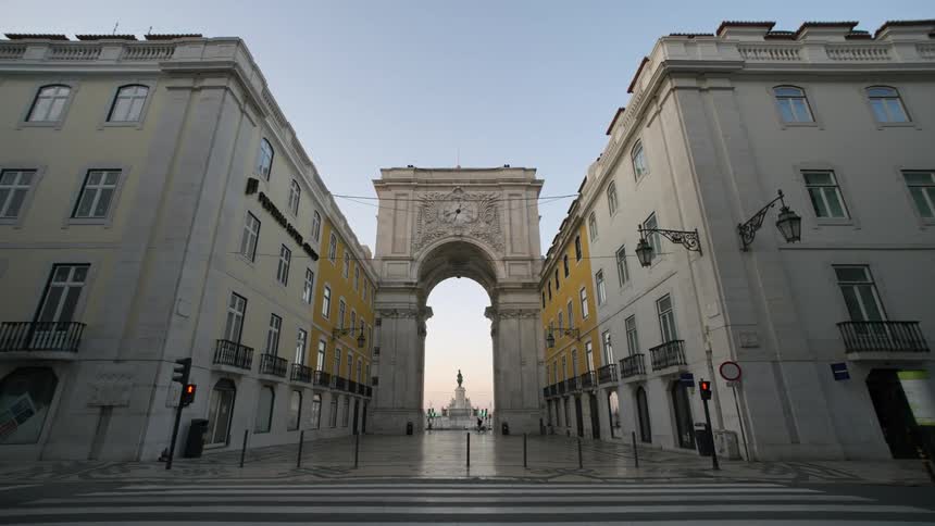 Classical buildings in an urban city with an arch in the background and a statue