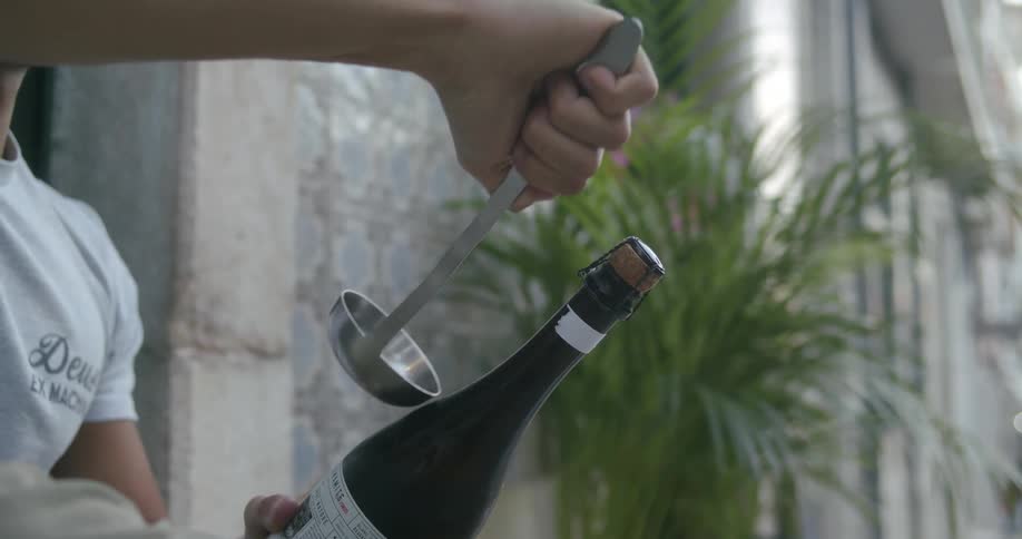 Womans hand with a ladle opening a champagne