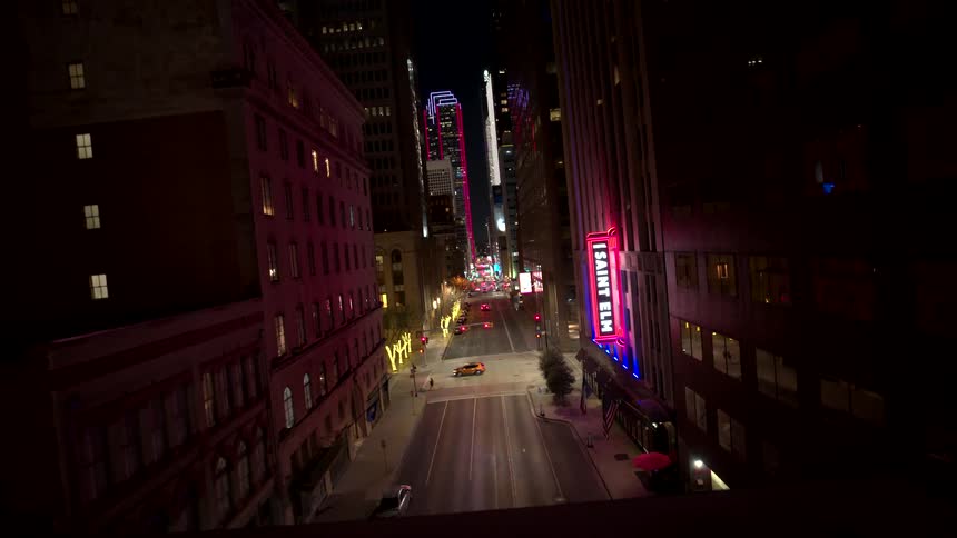 Aerial view of a bustling city street with neon signs illuminating storefronts