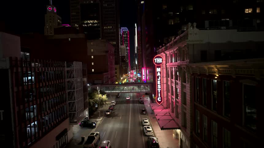 A downtown city street at night with cars driving by a theater