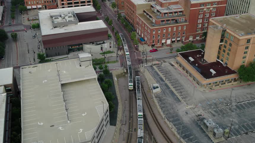 Aerial view of an urban area with buildings roads and two trains moving on tracks