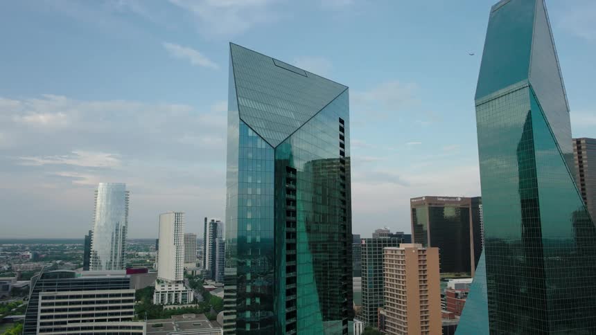 Urban skyline with several tall buildings highlighting two modern angular design skyscrapers made of reflective glass