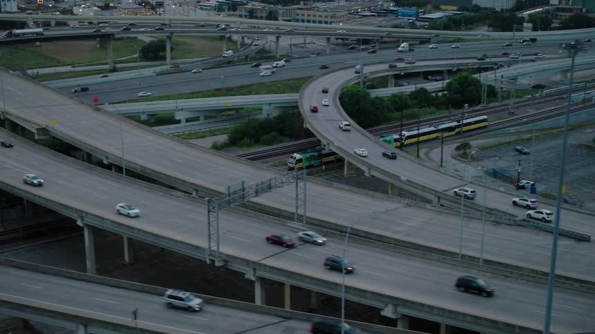 Complex network of viaducts and multilane roads featuring moving vehicles and a train