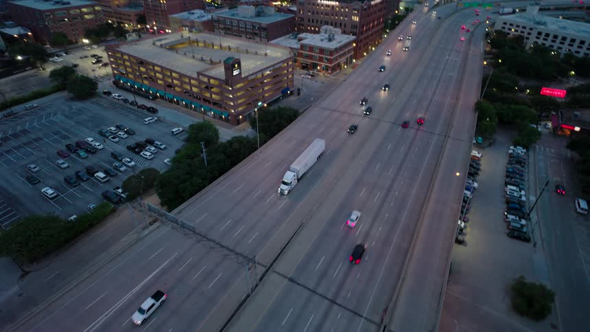 Aerial view of a white truck driving on a multilane highway running through the city