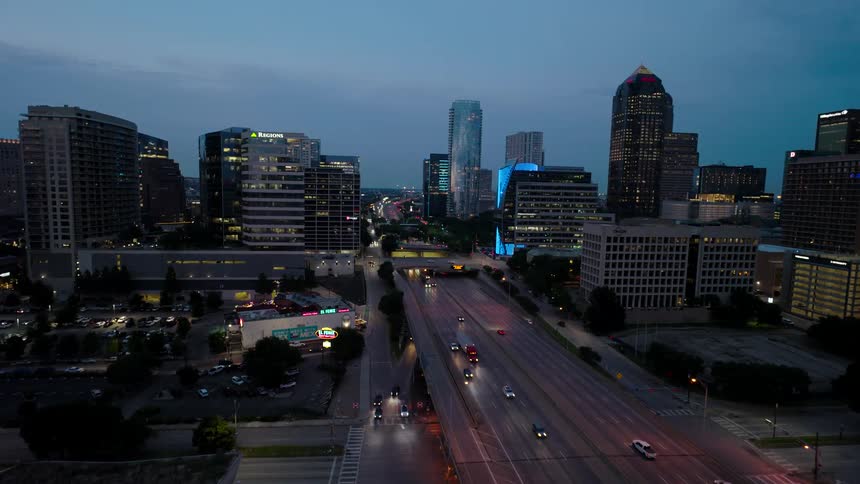 Highway with vehicle traffic in the middle of a metropolis with modern skyscrapers seen in the early evening