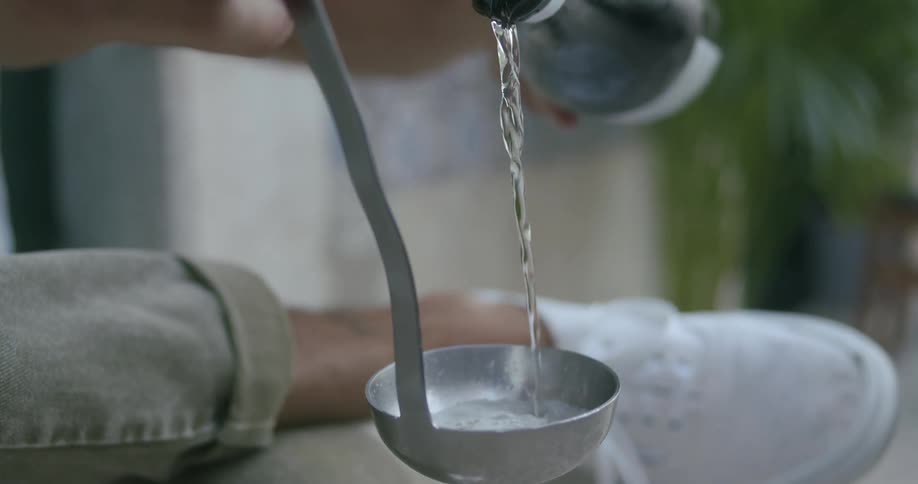 A clip of a person purring a drink on a spoon