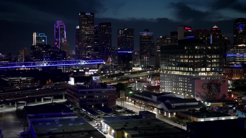 A metropolitan city at midnight with the lights of the buildings on and a construction crane illuminated in blue