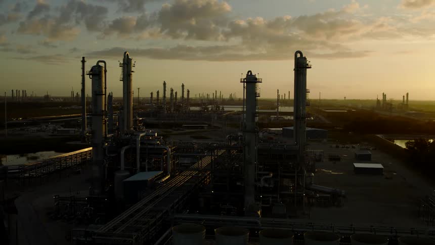 Aerial view of an orange sky and a refinery with towers