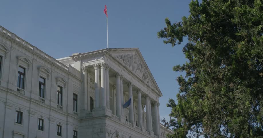 A large white government building with pillars against a blue sky