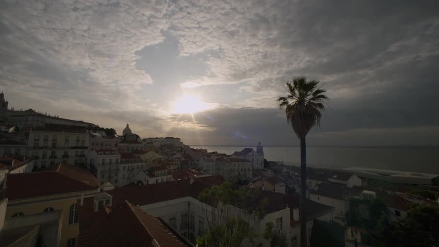 Scenic view of a coastal town at sunset with the sun low on the horizon illuminating the buildings and sea