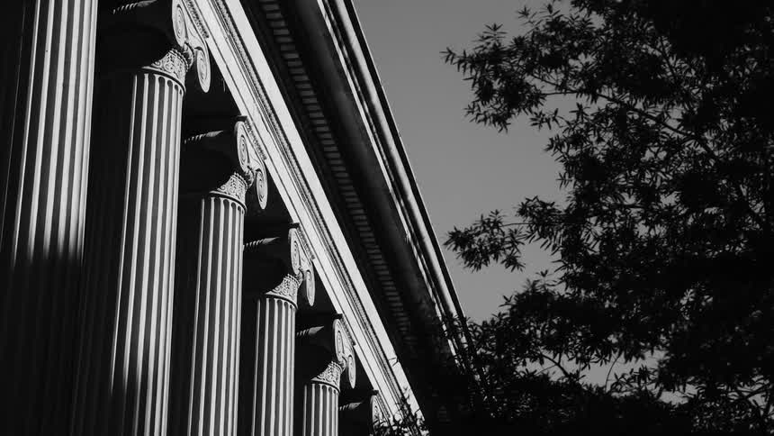 Closeup view of classical columns with vertical fluting and ornate capitals in black and white