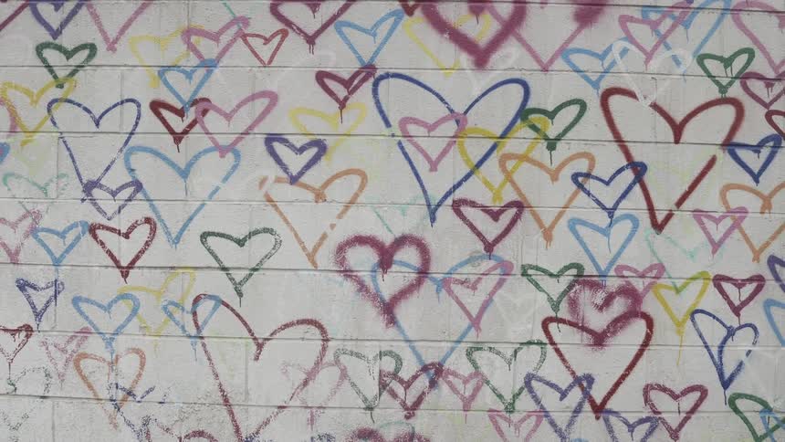 A close up clip of heart paintings on a white wall