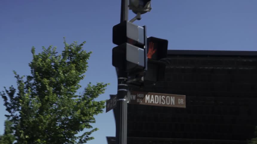 A traffic light with a red hand on the screen and below it there are two street name signs