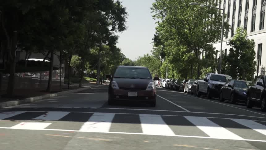Vehicle crosses an urban intersection during a sunny summer day