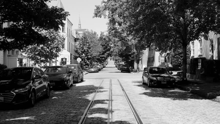 Cobblestone urban street with cars parked on the sides
