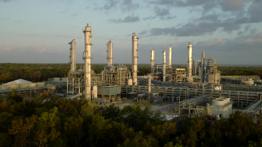 Industrial refinery with tall distillation columns and complex piping networks during sunrise or sunset