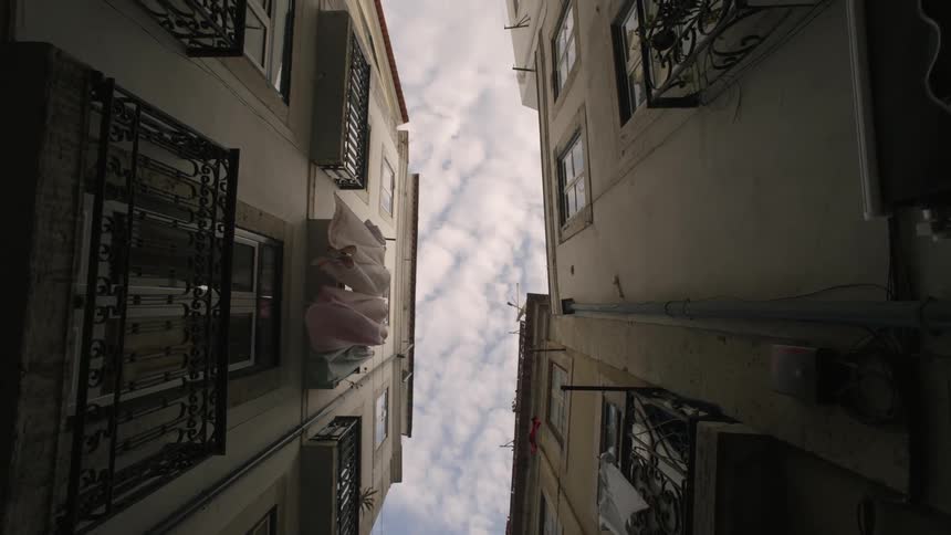 Upward view between two urban buildings with balconies and windows