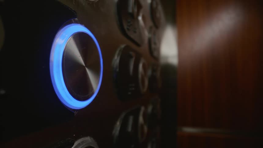 A finger presses an elevator button