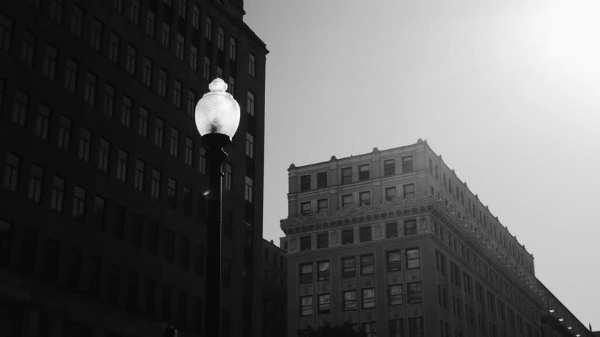 Black and white cityscape with a lit street lamp in the foreground