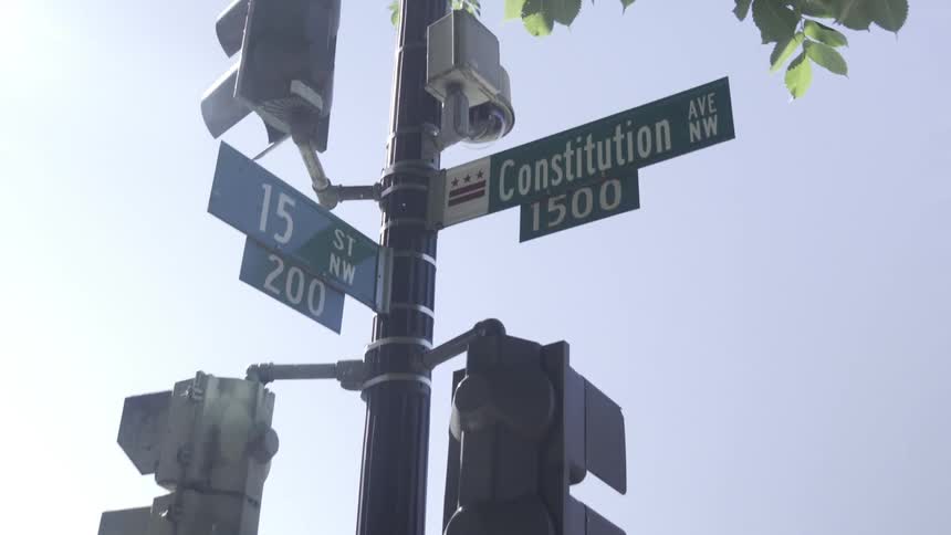 Street signs at an intersection mounted on a pole with traffic signals