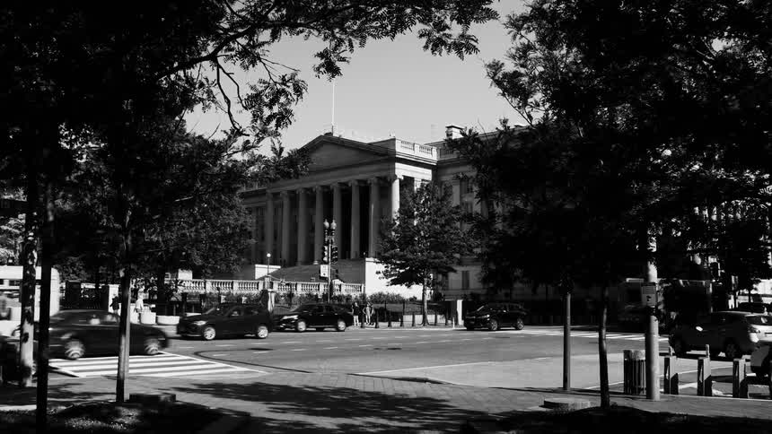 Urban scene highlighting a classical building with columns in the background and a pedestrian crossing in the foreground with a street