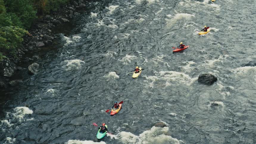Aerial of a small group of people kayaking on a river on an autumn day