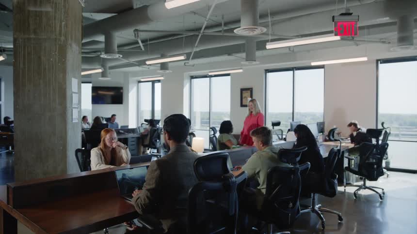 Open floor office space with people working at desks some using computers