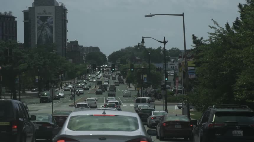 Busy urban street lined with cars during the day