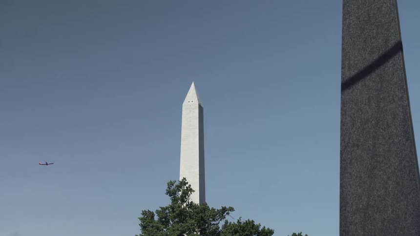 An airplane flying behind the washington monument
