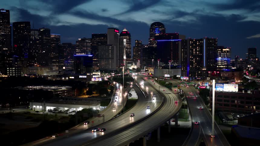 Night cityscape with illuminated buildings and a busy curved highway