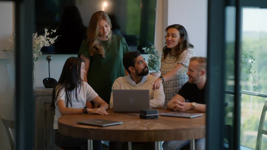 Group of five people including men and women in an office room talking