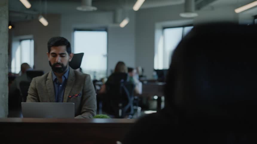 People working on their laptops or talking to each other on a large office open space