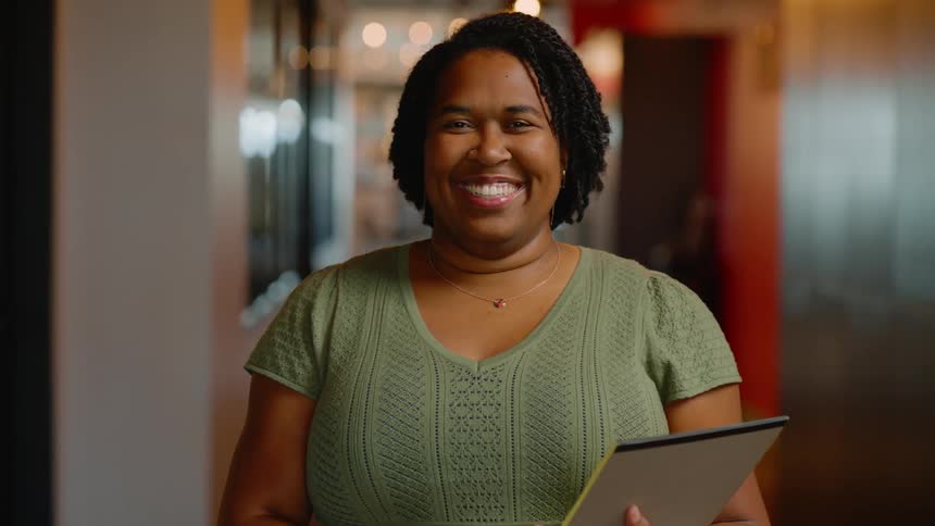 Happy woman portrait holding notepad while standing in a hallway of a building