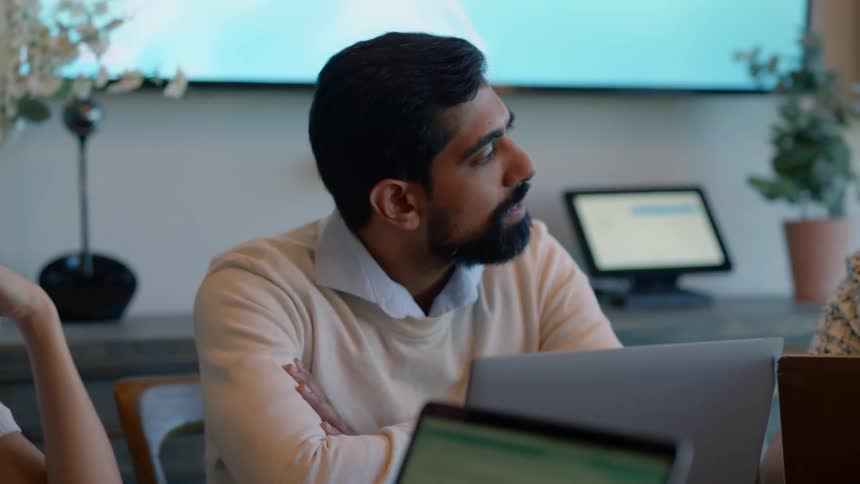 Man sitting in an office room with other people talking