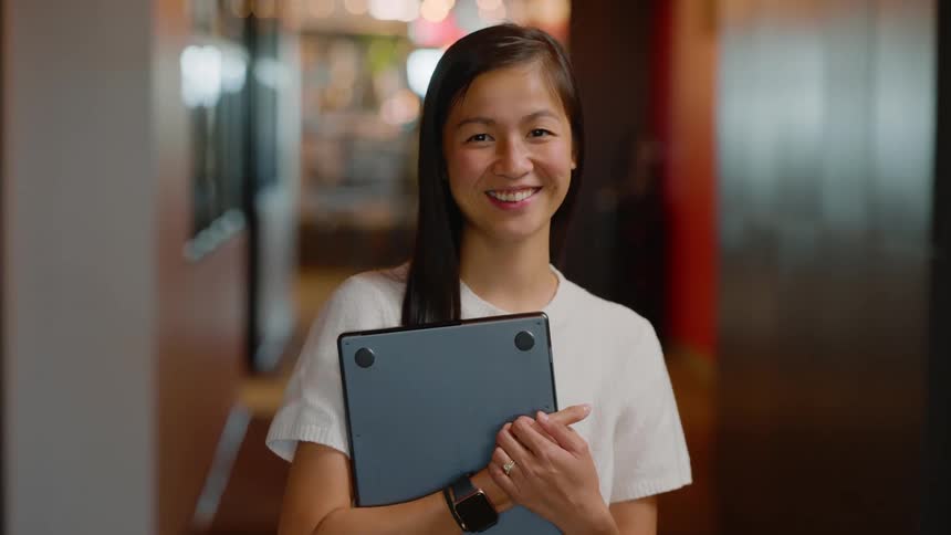 Woman holding a closed laptop and smiling