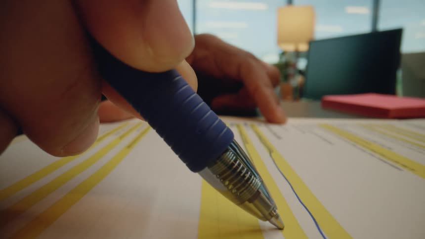 Close up of a finger holding a pen and crossing out text on a paper