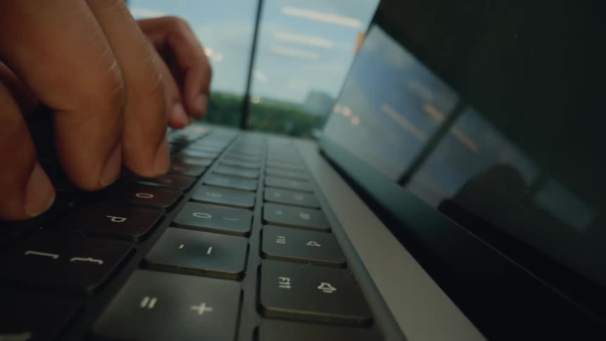 Closeup of hands typing on a laptop keyboard