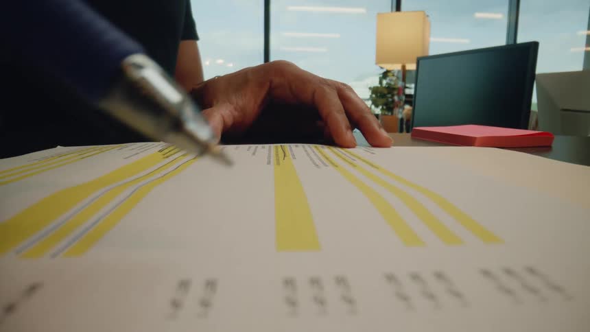 Close up of a hand holding a pen and crossing out text on a paper