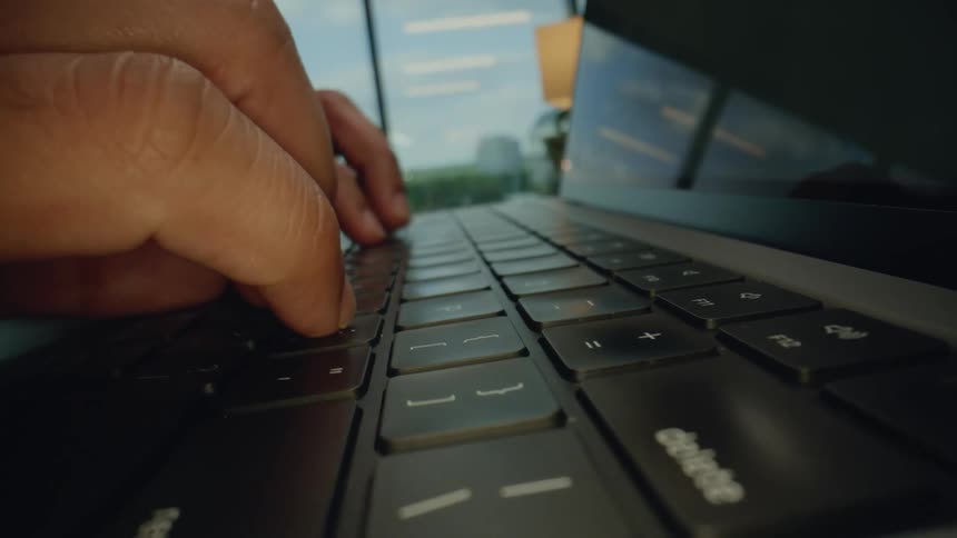 Closeup view of a persons hand typing on a laptop keyboard