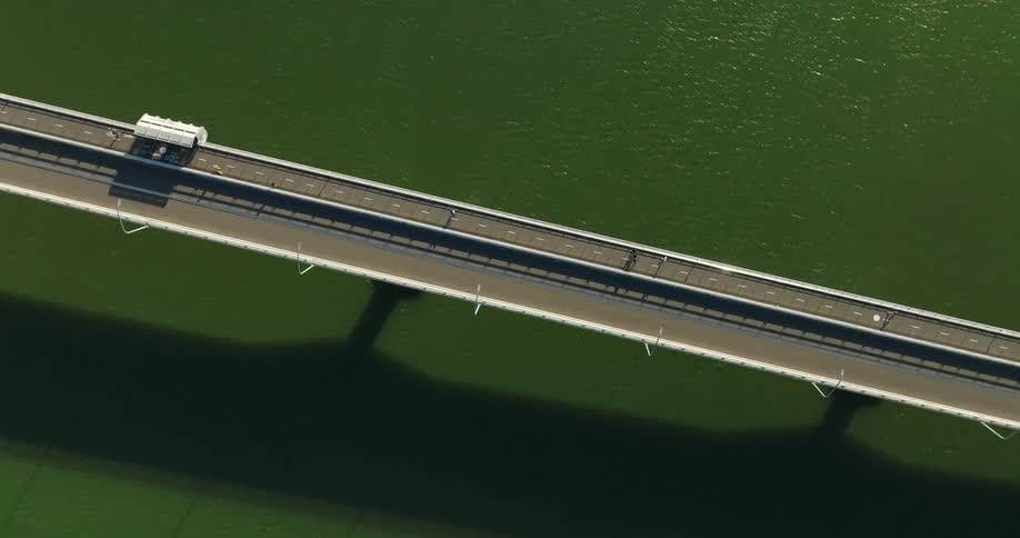 Aerial view of a long bridge over a green body of water