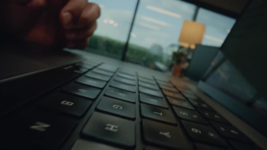 Hands using a trackpad on a laptop in an office
