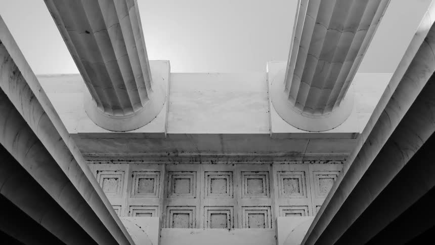 Black and white footage of two large columns with ornate detailing