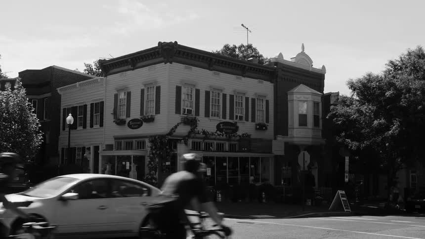 City street with vehicle and cyclist traffic and a classic corner building in the background
