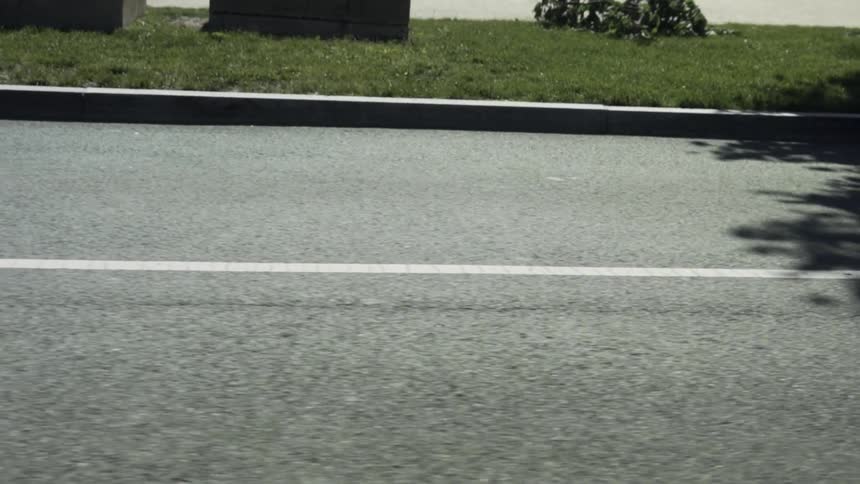Two black cars driving along an asphalt street with a white stripe in the middle