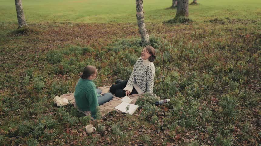 Two women sitting in a forest laughing