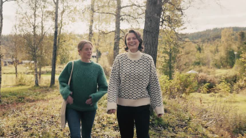 Two happy women walking through a treelined environment talking to each other