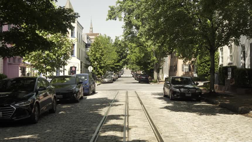 Cobblestone street with parked vehicles in an urban city