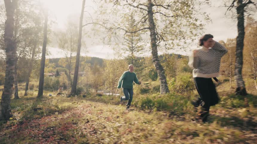 Two women run through a wooded area