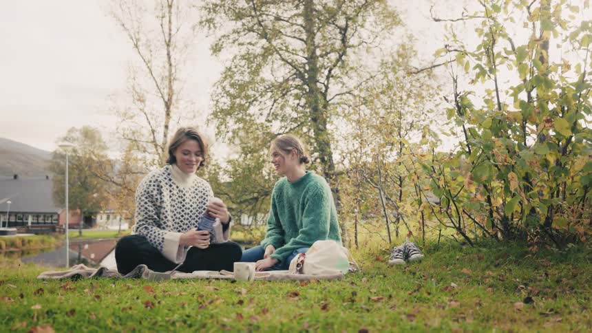 Two women sitting on a blanket in the grass enjoying a moment outdoors
