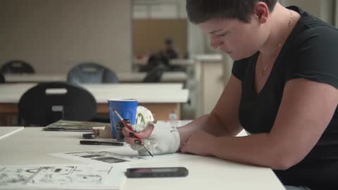 A woman paints while sitting at a table